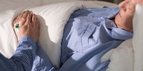 Pflegekraft hält Hand eines alten Menschen